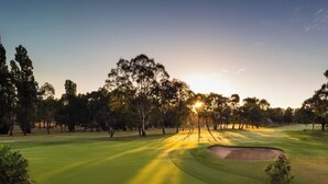 Un campo de golf al atardecer con árboles y cielo despejado.