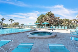 A pool area with lounge chairs and umbrellas, a hot tub, and a tree in the background. - ☀Stunning Beachfront Condo🐬Price Drop!🌴Private Balcony (Indian Rocks Beach)