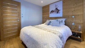 Un dormitorio con una cama de madera, un cuadro de un ciervo en la pared y una puerta de madera.