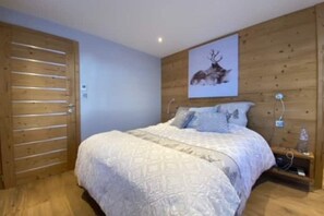A bedroom with a wooden bed, a wall-mounted artwork of a deer, and a wooden door. - Superb vacation chalet with pool & jacuzzi - La Bresse (La Bresse)