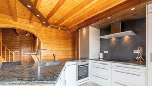 Una cocina moderna con paredes de madera, armarios blancos y encimeras de granito.