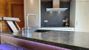 Una cocina moderna con encimera de granito, grifo de acero inoxidable y campana extractora integrada.