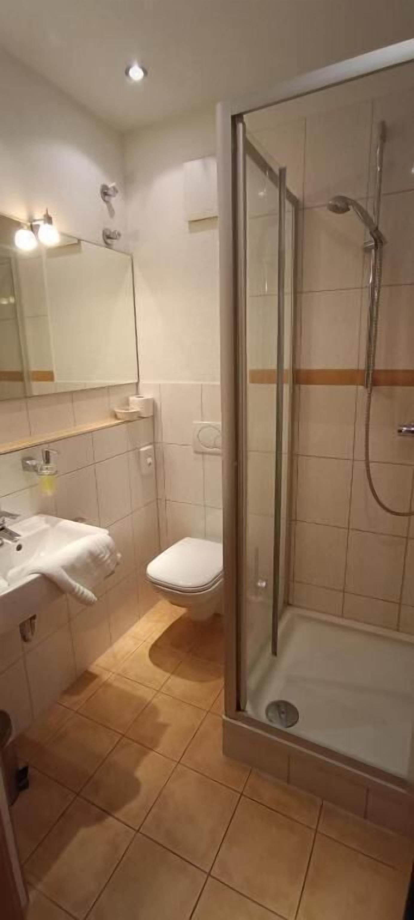 A bathroom with a glass-enclosed shower, a toilet, and a sink with a towel.