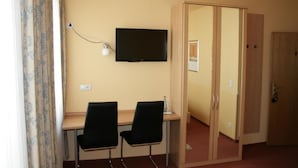 Una stanza con una scrivania, due sedie, una televisione e un armadio.