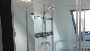 Un bagno moderno con cabina doccia in vetro, lavandino con specchio e cestino.
