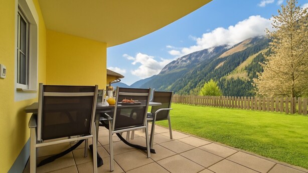 A patio with a yellow wall, a table with chairs, and a mountain view. - Cozy apartment with 2 bedrooms, private terrace and mountain view (Flattach)
