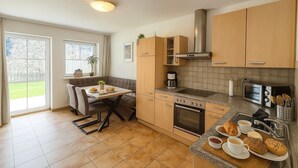 A modern kitchen with a dining area, a large window, and a view of the outdoors. - Cozy apartment with 2 bedrooms, private terrace and mountain view (Flattach)