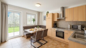 A modern kitchen with a dining area, large windows, and a view of the garden. - Cozy apartment with 2 bedrooms, private terrace and mountain view (Flattach)