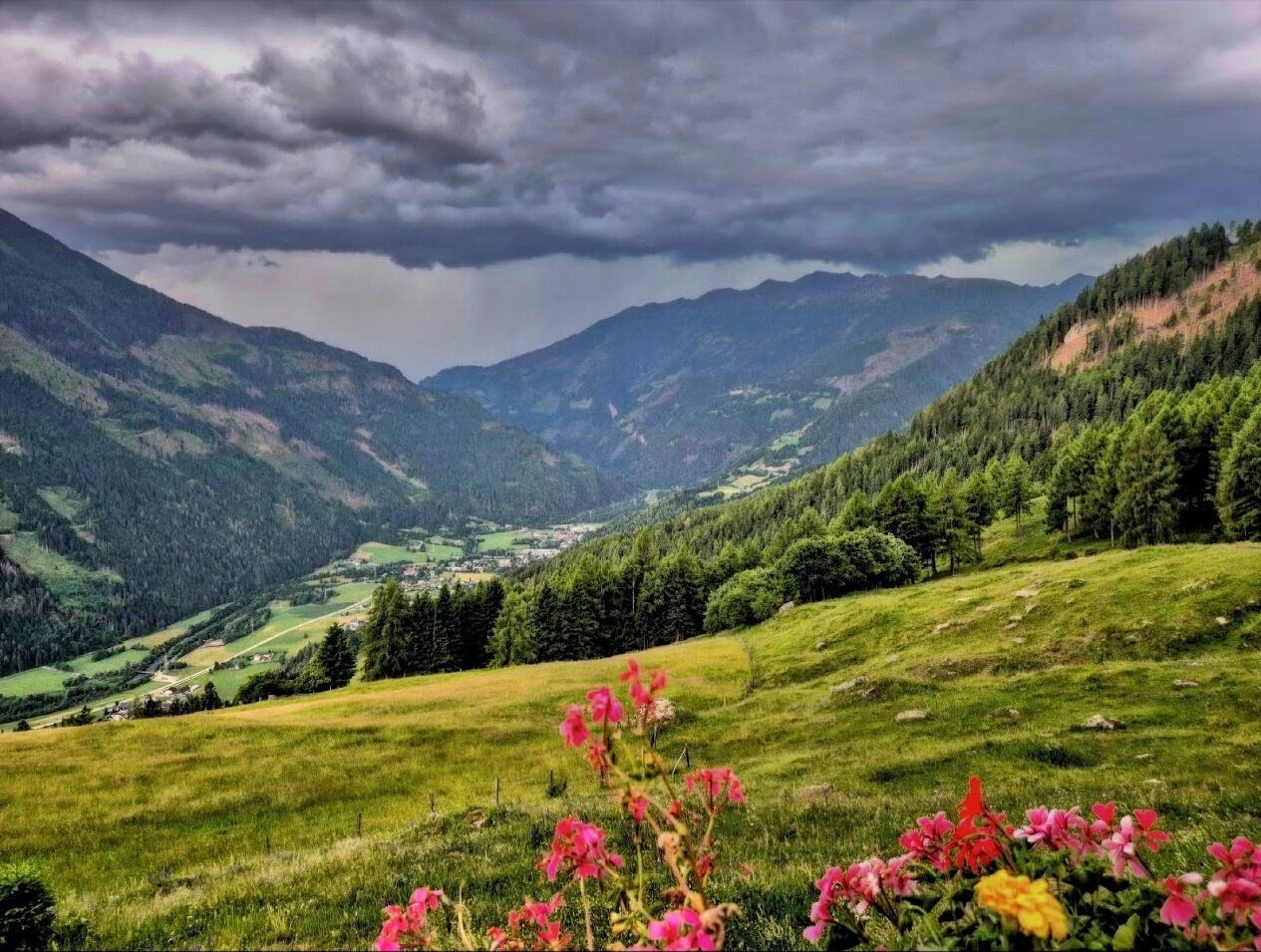 A mountainous landscape with a valley, green fields, and a small village.