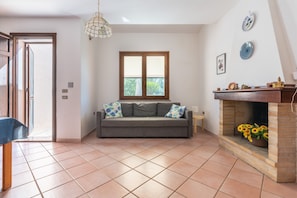 Una sala de estar con un sofá, una chimenea, una ventana y una puerta.