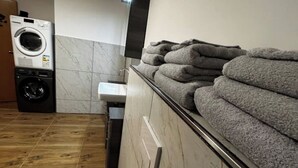 A laundry area with stacked towels, a washing machine, and a sink. - Freshly renovated and large bright apartment in Löhne (Löhne)
