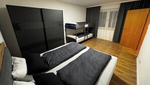 A bedroom with a bed, a wardrobe, a bunk bed, and a window with curtains. - Freshly renovated and large bright apartment in Löhne (Löhne)