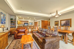 A spacious living room with a leather sofa, wooden dining table, and a chandelier. - Experience the Rocky Mountains of Steamboat from the comfort and convenience of (Steamboat Springs)