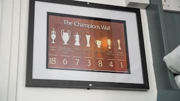 A framed display titled "The Champions Wall" with trophies and numbers representing various football championships.