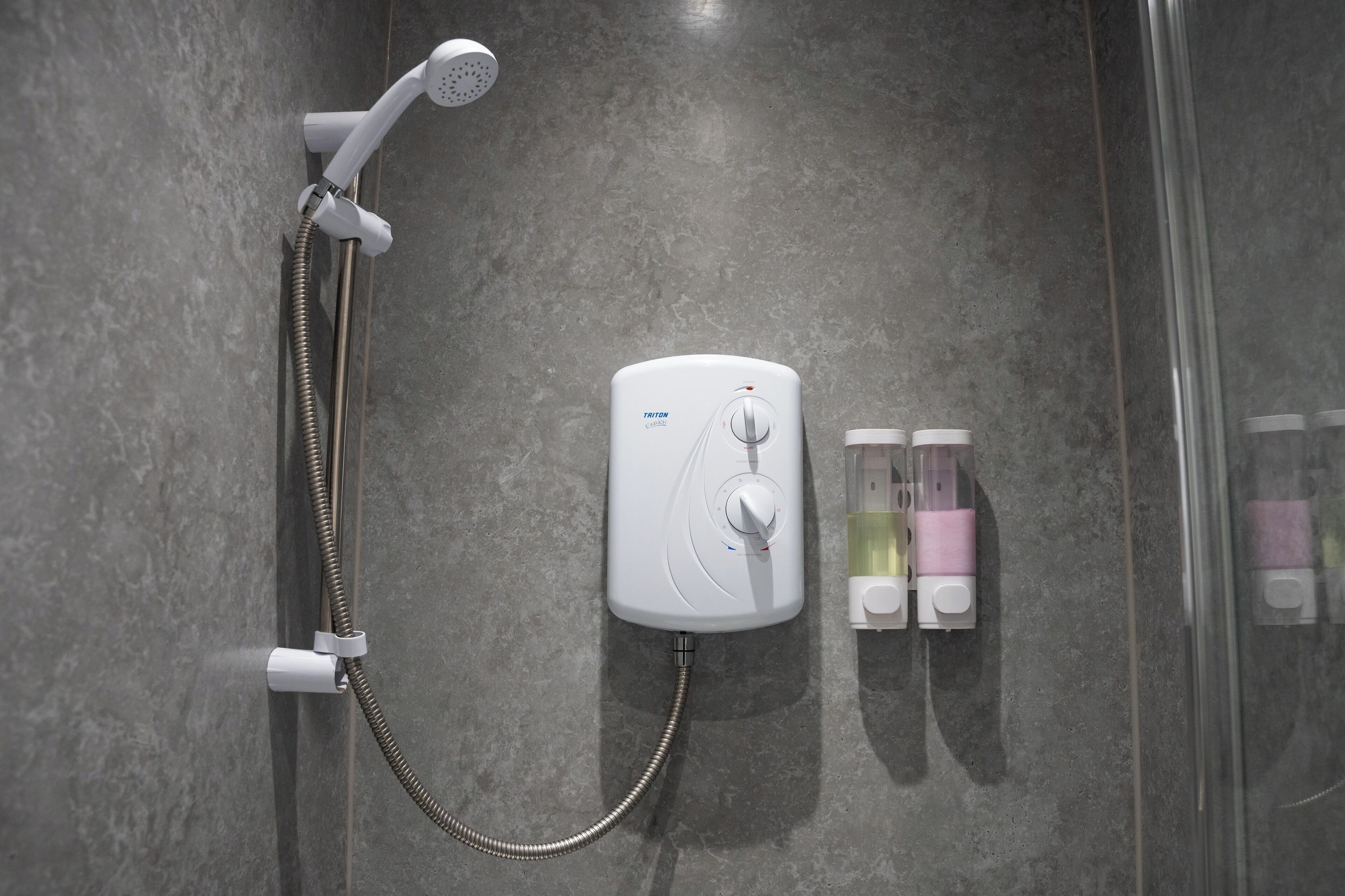Une douche moderne dotée d’un pommeau de douche à main et d’un panneau de commande fixé au mur.