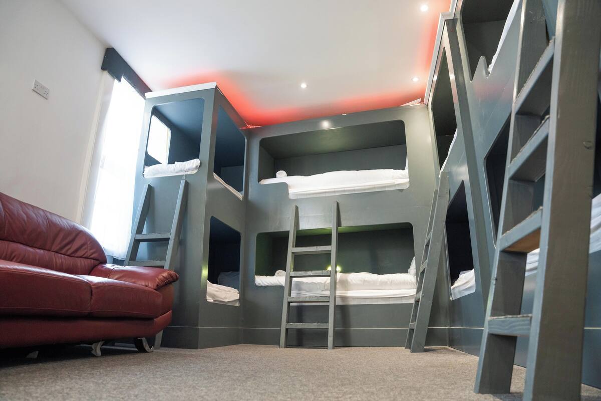 Una habitación con literas, una escalera y un sofá rojo.