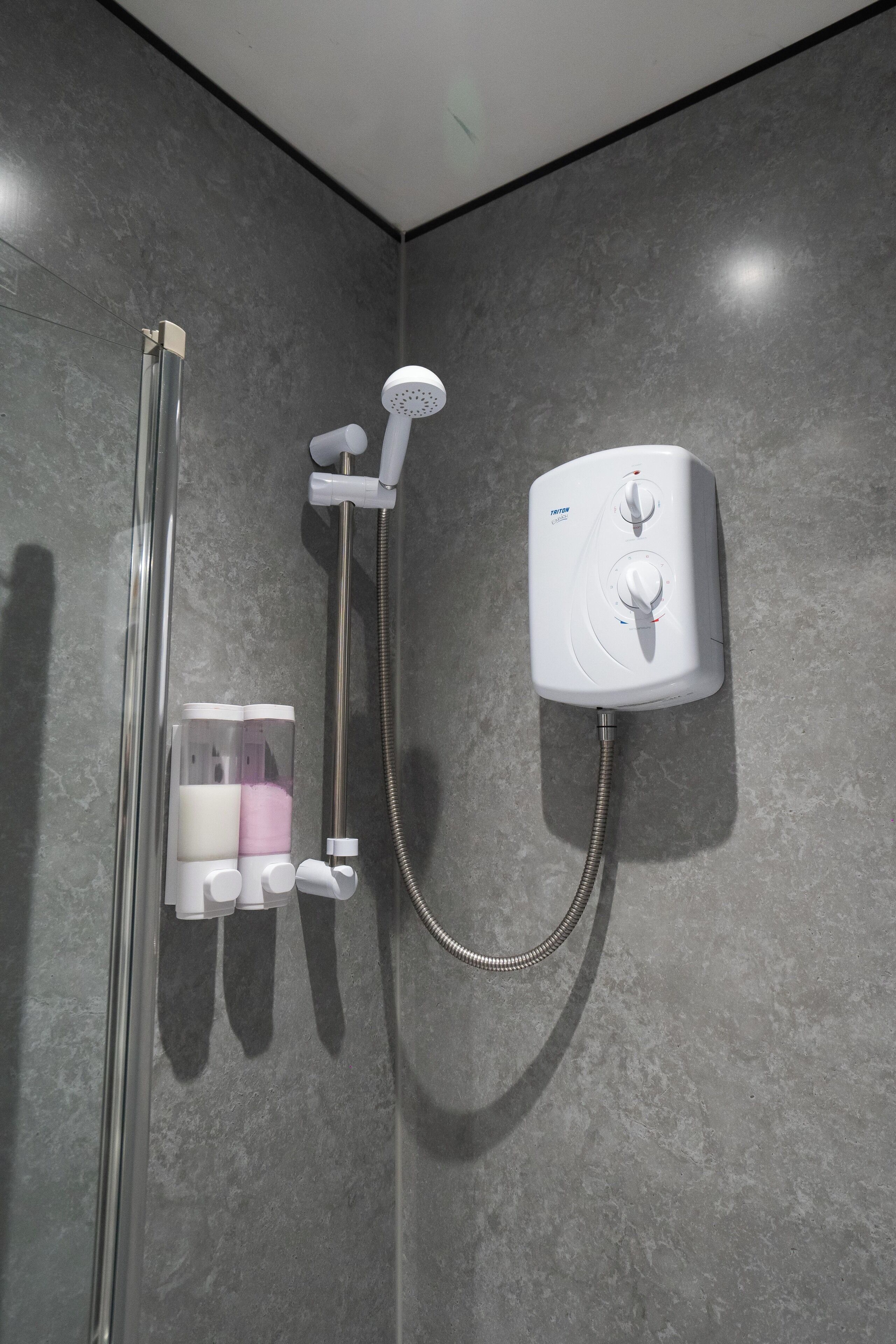 A modern shower with a handheld showerhead and a wall-mounted control panel.
