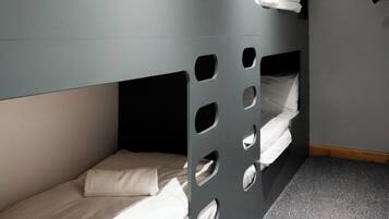 Ein Schlafraum mit Etagenbetten, grauer Wand und geneigter Decke.