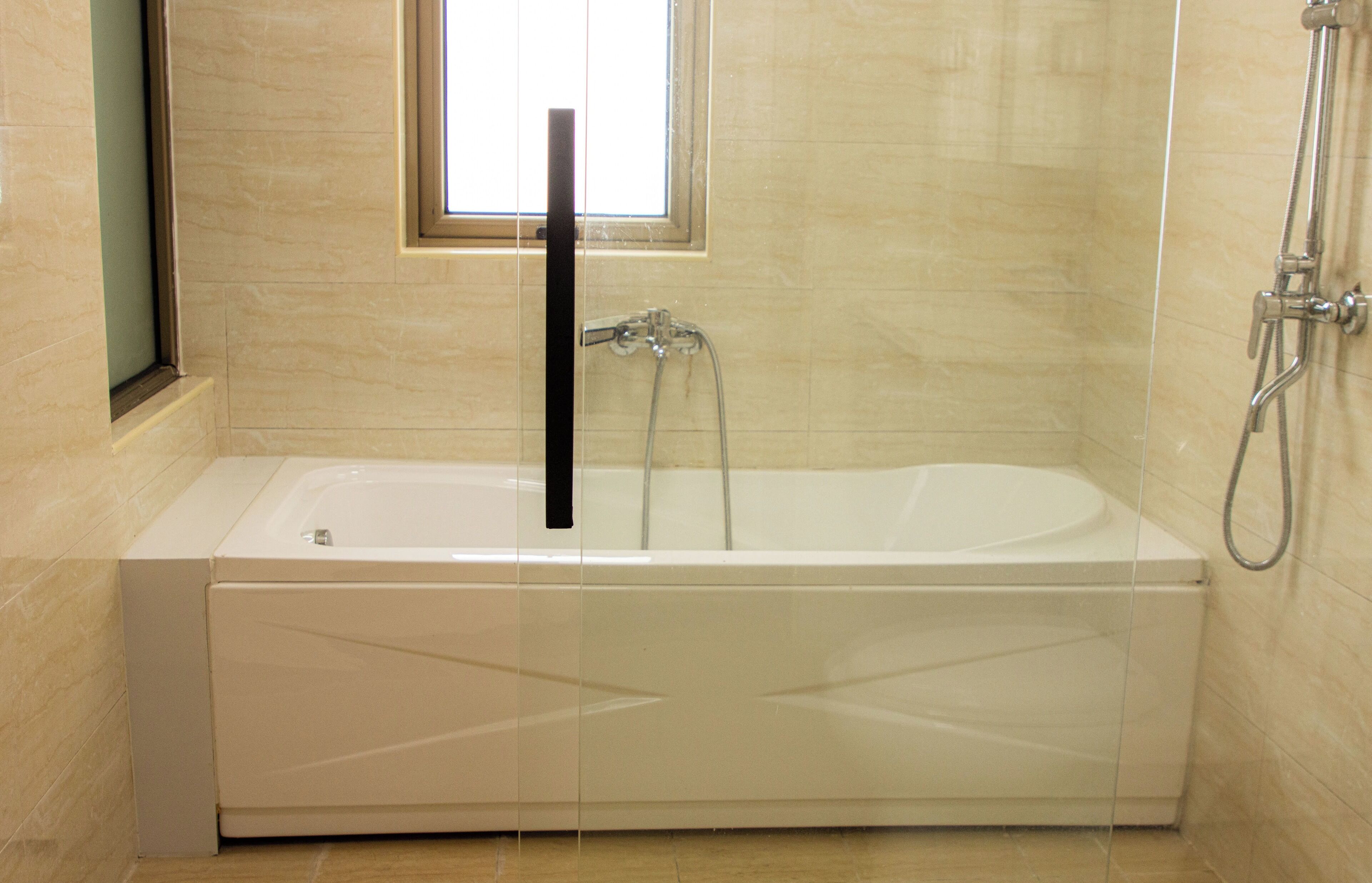 A modern bathroom with a freestanding bathtub, a shower area, and a window providing natural light.