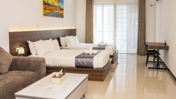 A hotel room with two beds, a desk, a chair, a couch, and a painting on the wall. - A One Oasis River View Hotel (Phnom Penh)