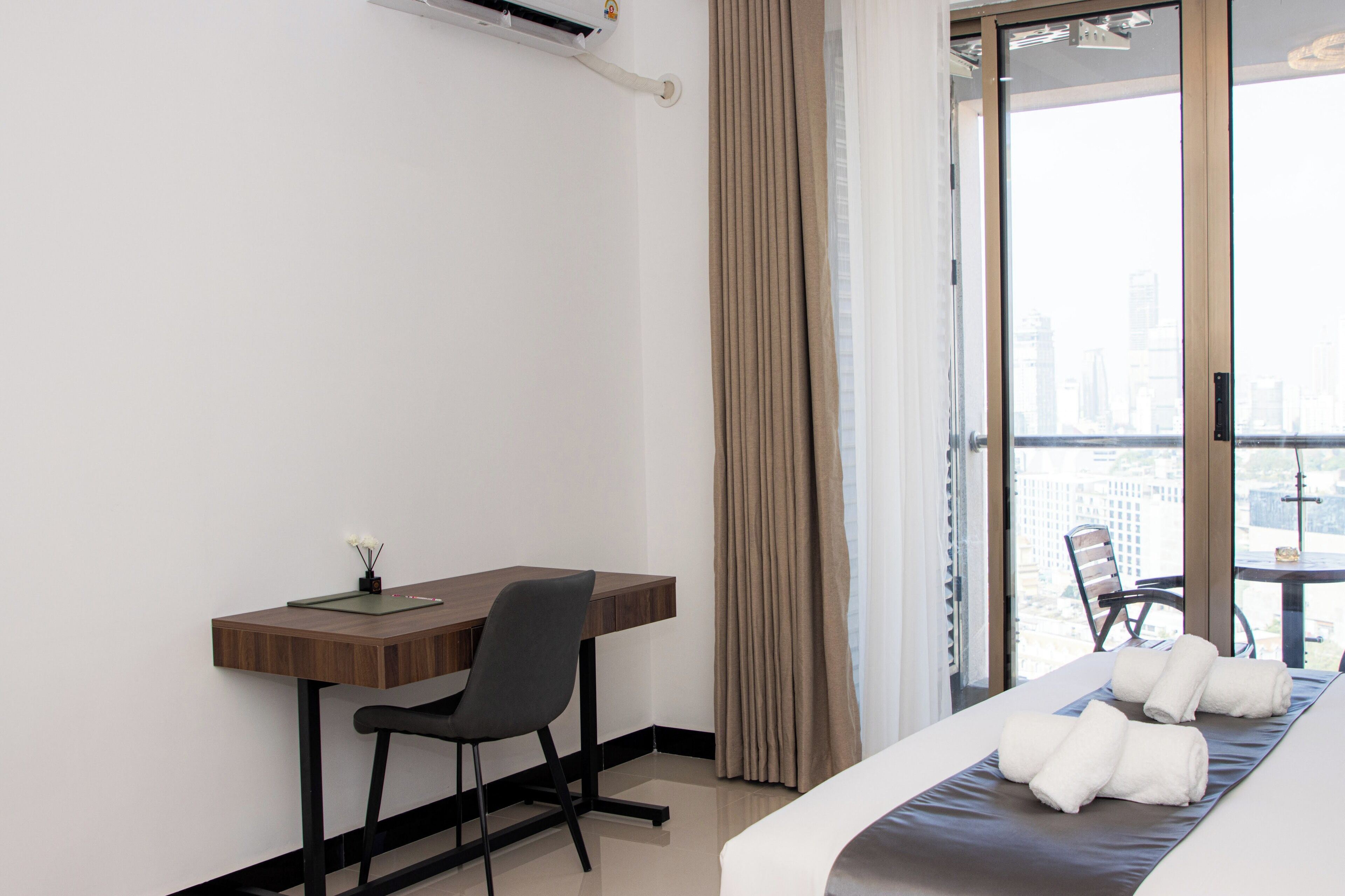 A hotel room with a desk, chair, and a bed with towels.