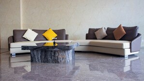 A modern living room with two sofas, a marble coffee table, and a plain wall. - A One Oasis River View Hotel (Phnom Penh)