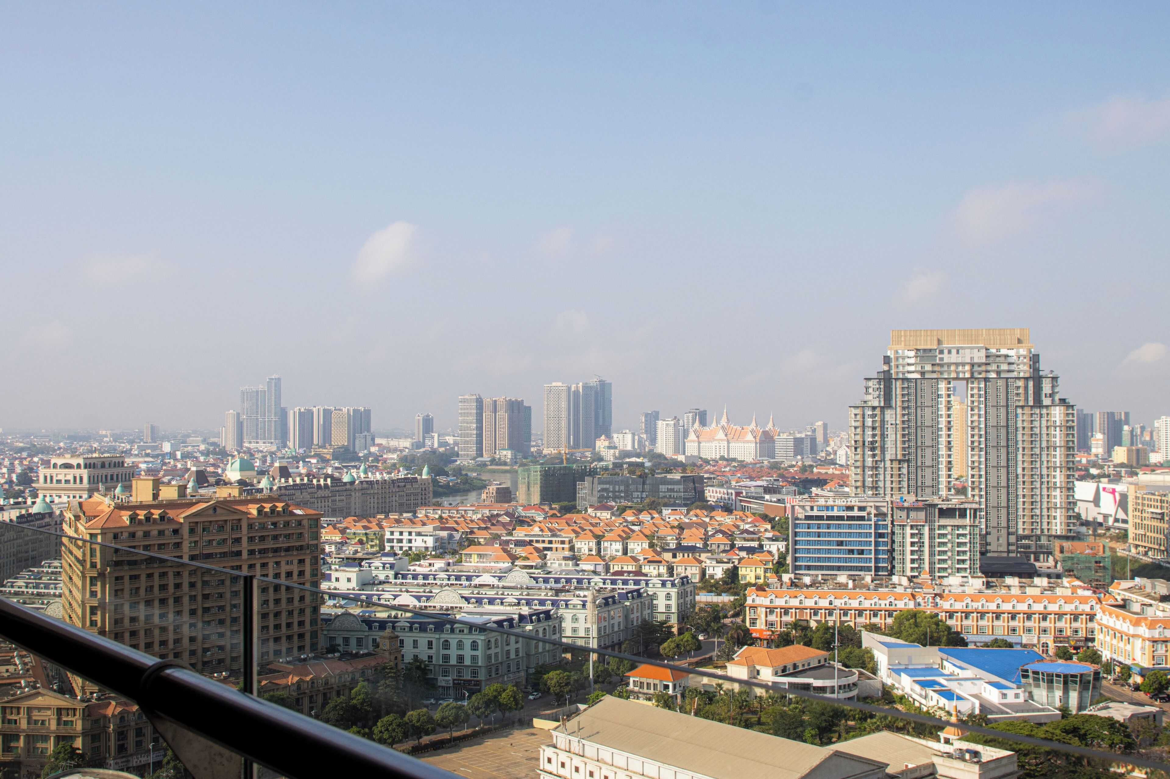 A cityscape with a mix of modern and traditional buildings, including a prominent high-rise with a unique roof design.