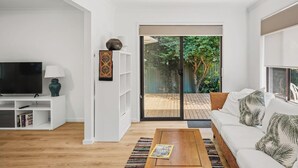 Un salon moderne doté d’un téléviseur, d’une bibliothèque et d’un canapé offrant une vue sur le jardin.