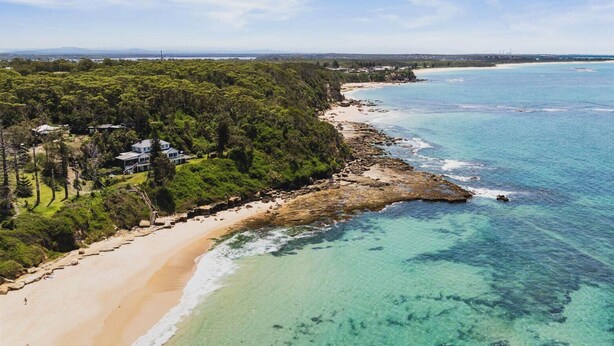 Une propriété située sur la côte, avec une plage, un accès à l’océan et une zone boisée.