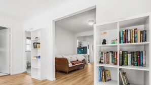 Un salon moderne avec un canapé, une bibliothèque et une porte blanche donnant sur une autre pièce.