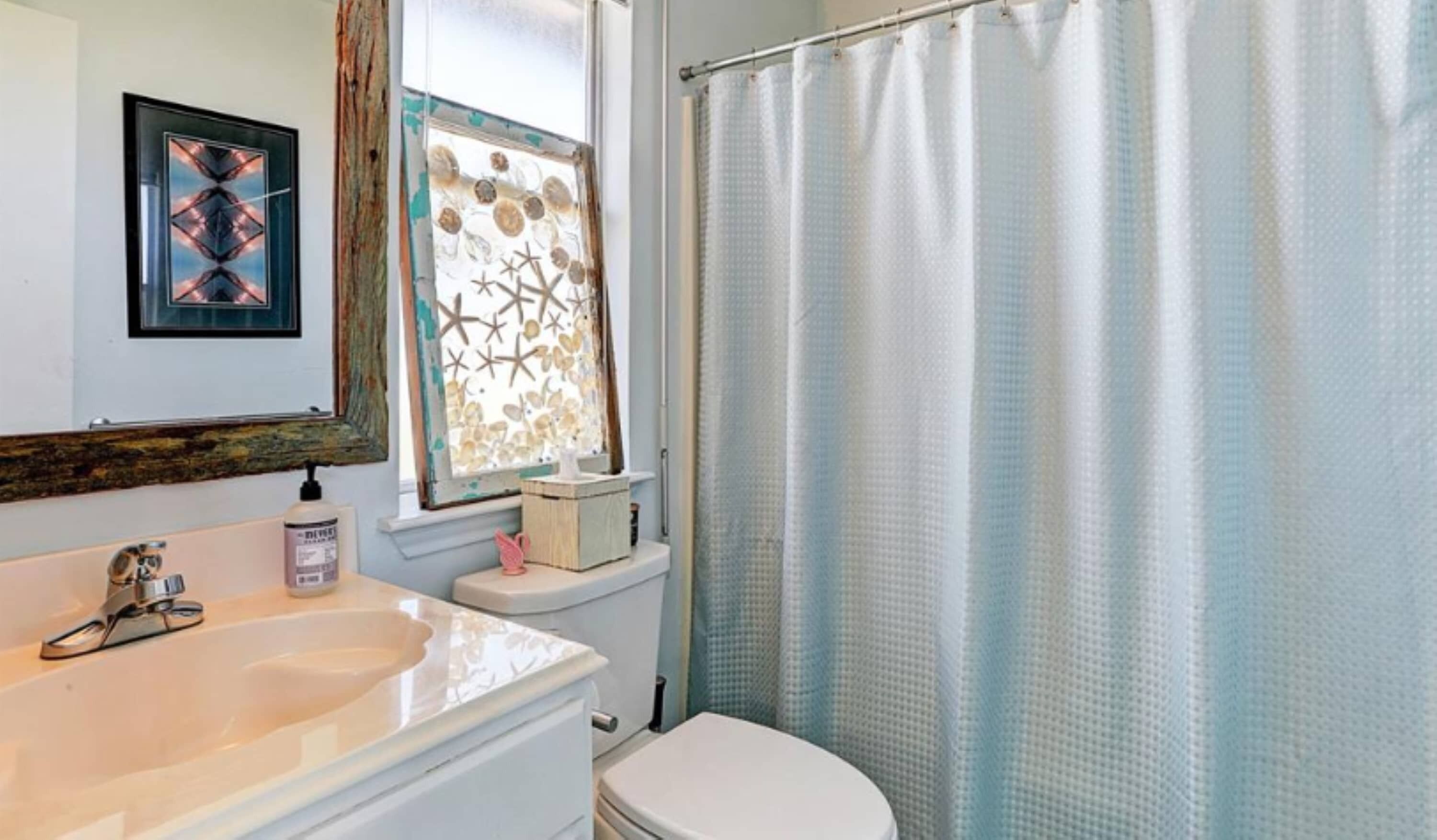 A bathroom with a white sink, a toilet, and a shower curtain.