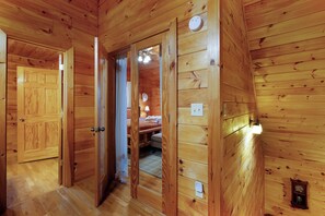 A wooden cabin interior with a bedroom, a bathroom, and a hallway. - Golden Acres - Morganton,GA (Morganton)