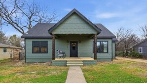A single-story house with a front porch, a visible number "15" on the door, and a clear sky. - The Bella - Modern Equestrian Home with Park Views near Weatherford Square! (Weatherford)