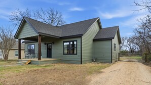 A single-story house with a gabled roof and a covered porch. - The Bella - Modern Equestrian Home with Park Views near Weatherford Square! (Weatherford)