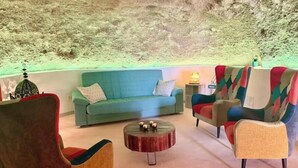 Una sala de estar con un sofá verde, una mesa de centro redonda y sillones coloridos.