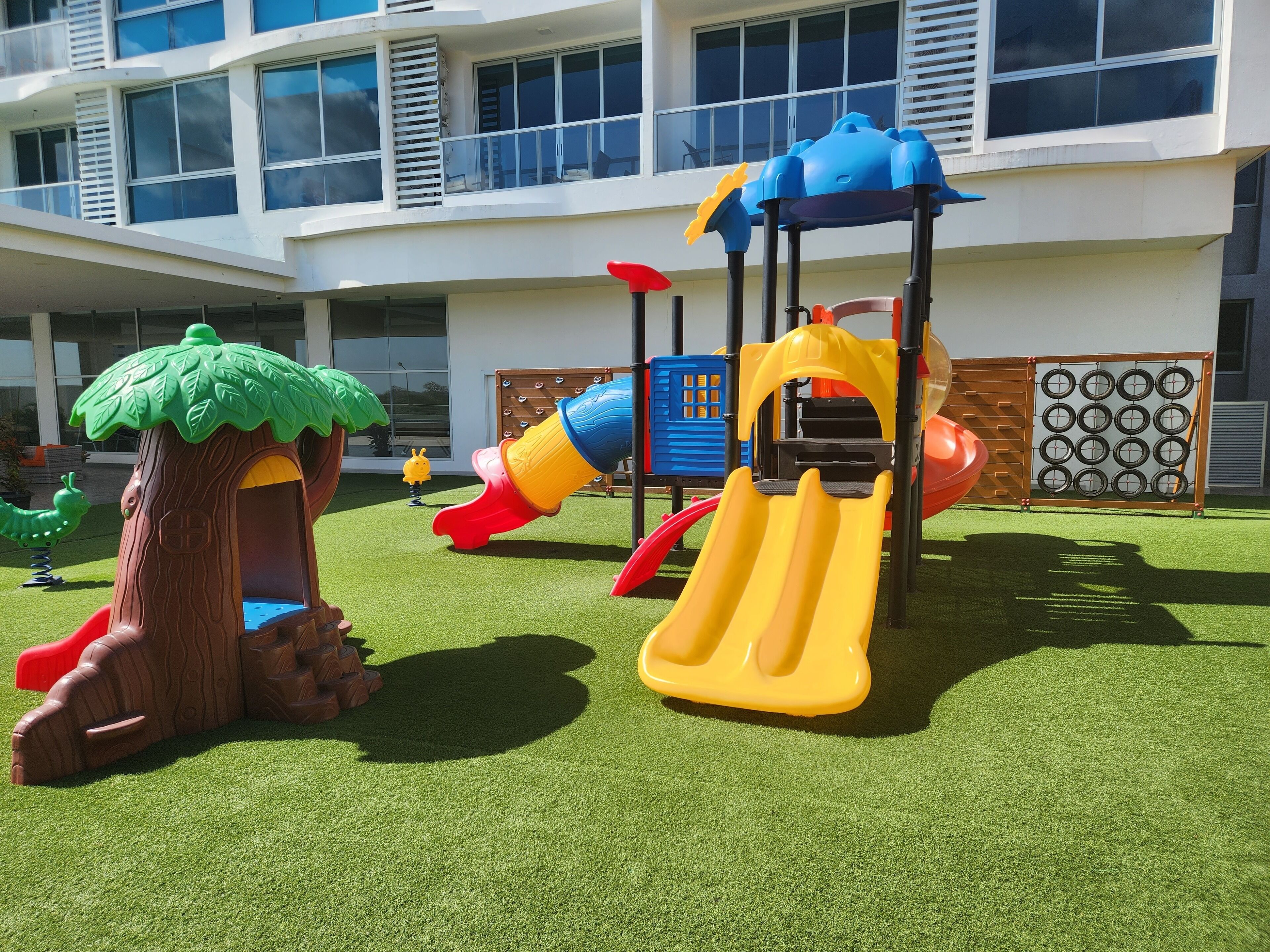 A children's play area with a slide, climbing structures, and a treehouse.