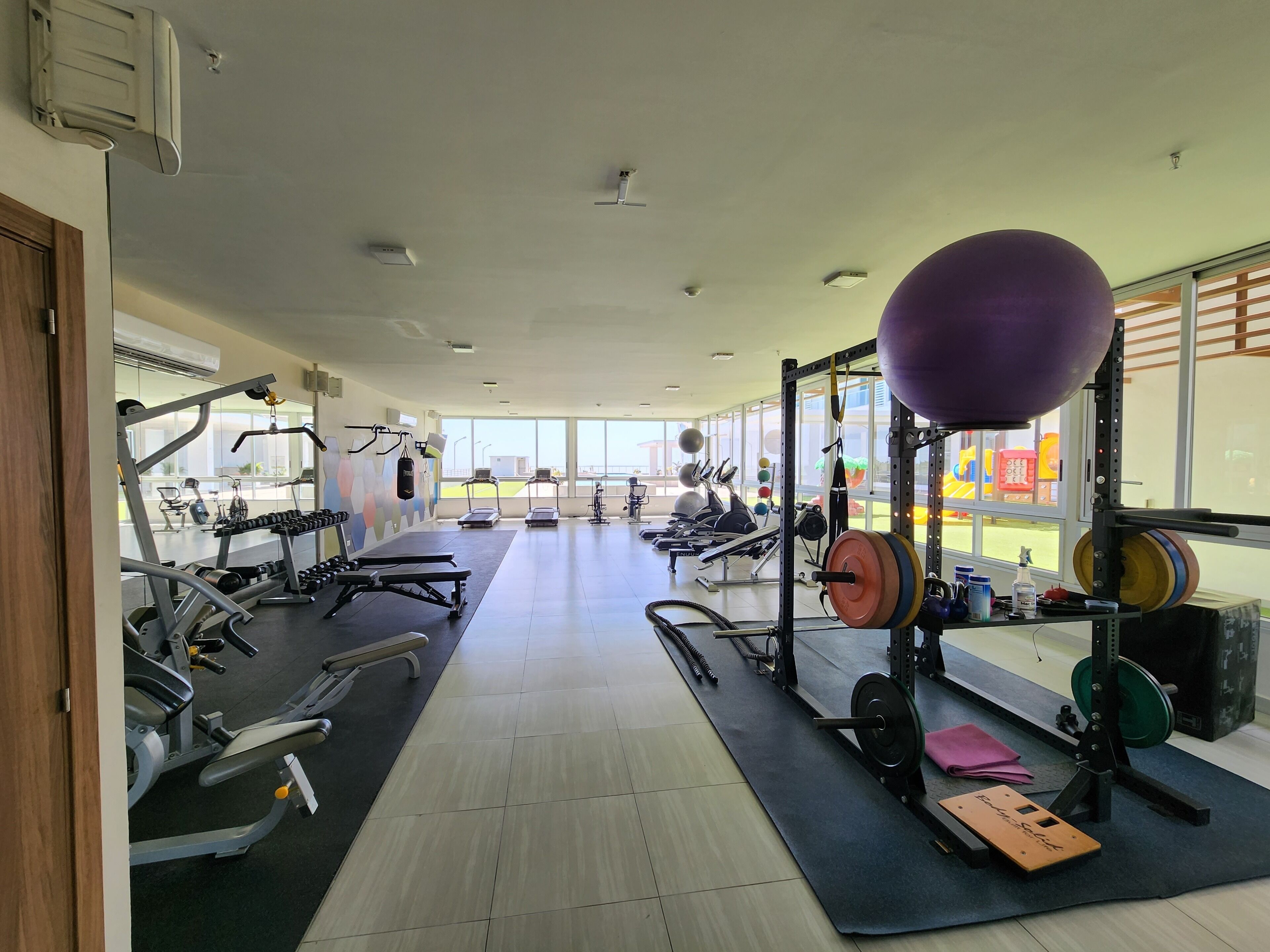 Ett gym med olika typer av träningsutrustning, inklusive löpband, styrketräningsmaskiner och fria vikter.