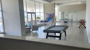 Un grand espace intérieur comprenant une table de billard, un fauteuil de massage et une table de snooker.