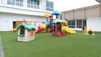 Un parque infantil con toboganes y estructuras para escalar frente a un edificio.