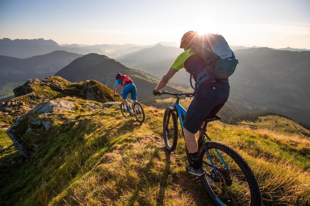 Deux cyclistes sur un sentier de montagne, avec une vue panoramique sur les montagnes lointaines.