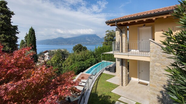 Une maison en pierre à deux étages, dotée d’une piscine, d’un balcon et offrant une vue sur la mer et les montagnes.