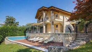Une maison à deux étages avec une façade en pierre, un balcon et une piscine.