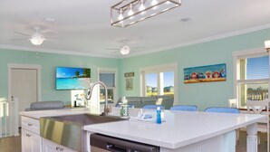 A kitchen with a dishwasher, a sink, and a dining area with chairs. - ☀️ Short Walk to Beach - Easy Beach Access - Blue Pelican ☀️ (Mexico Beach)