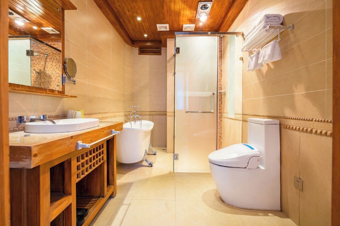 A modern bathroom with a wooden vanity, a bathtub, a toilet, and a glass shower enclosure.