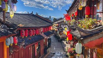 A narrow street with traditional architecture, red lanterns, and stone paving.
