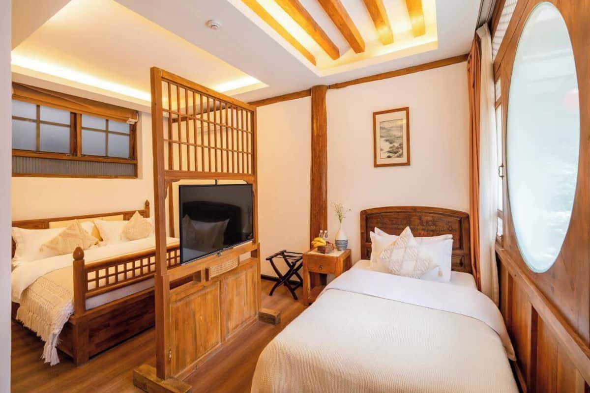 A room with a bed, a TV, a wooden partition, and a window.