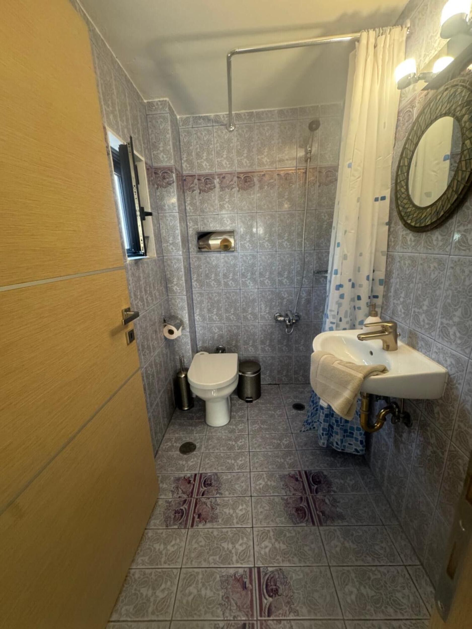 Un baño con inodoro, lavamanos, ducha y espejo.