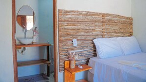 Een slaapkamer met een houten hoofdbord, een nachtkastje met een vaas en een bed met witte lakens.