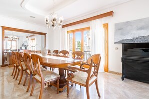 A dining room with a round table, wooden chairs, a chandelier, and a fireplace. - Holiday Home 'Can Maro' with Private Terrace, Balcony and Wi-Fi (Santa Margalida)