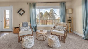 A living room with two wicker chairs, a round coffee table, and a small side table. - Expansive Decks, Two Living Areas with Fireplaces! (Lincoln City)